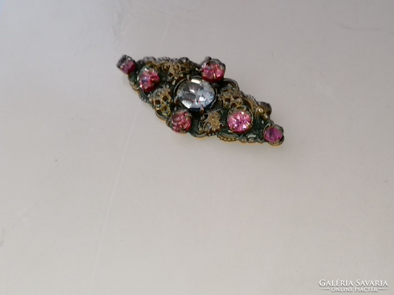 Bross kitűző központi fehér kővel és és több pici pink színű kővel díszítve.