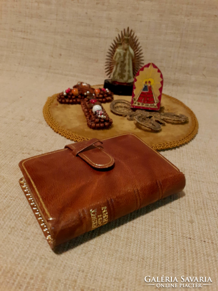 Old prayer book with a handmade cross and saints on a velvet tablecloth