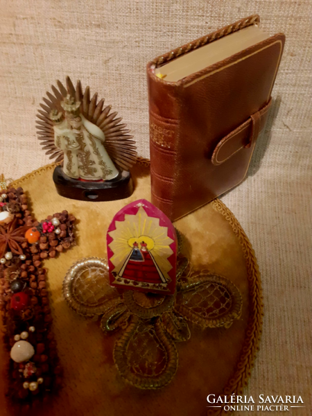 Old prayer book with a handmade cross and saints on a velvet tablecloth
