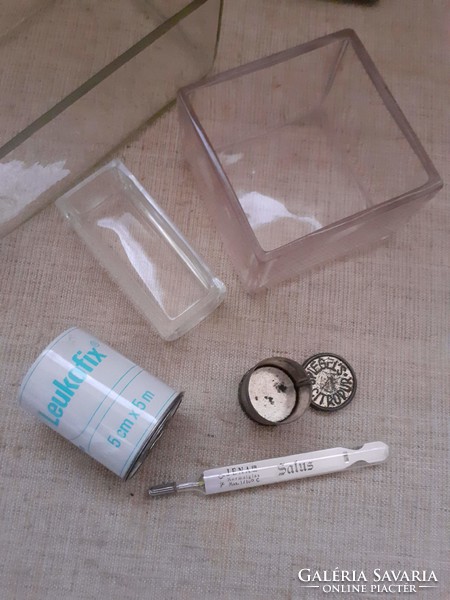 Old medical glass containers inside a thermometer with a metal case and a metal jar of wound adhesive