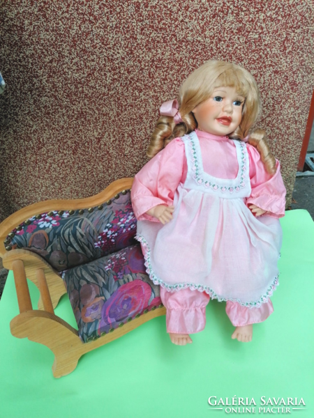 Old porcelain doll on a large wooden upholstered sofa