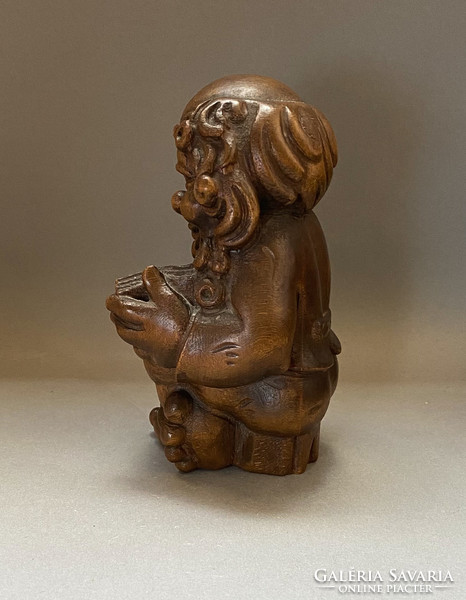 Old, reading leprechaun, dwarf. Carved wooden figure.