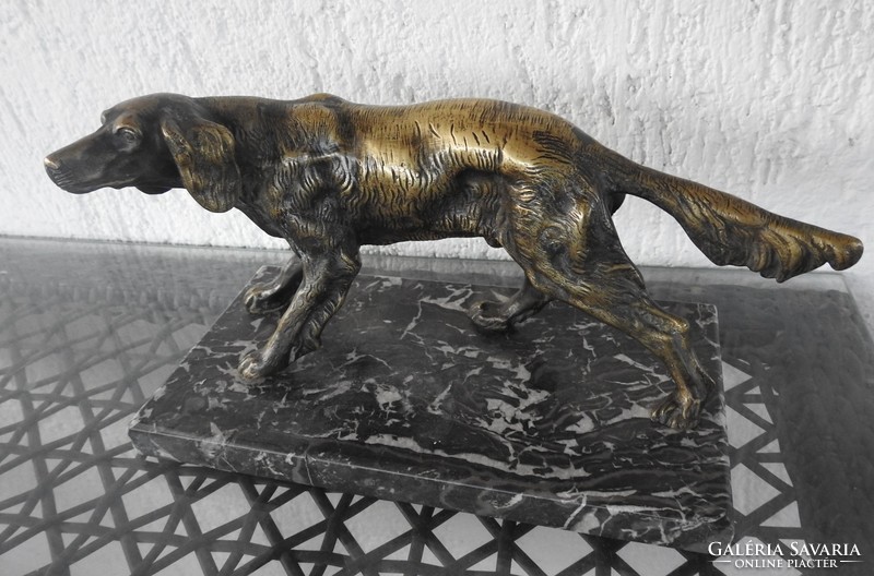 Large bronze dog sculpture on a marble pedestal