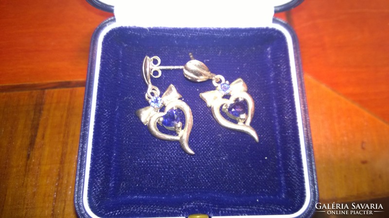 Silver bow earrings with blue stone-studded ears