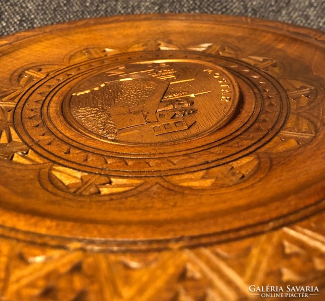 Wooden plate with a metal relief depicting most in the middle