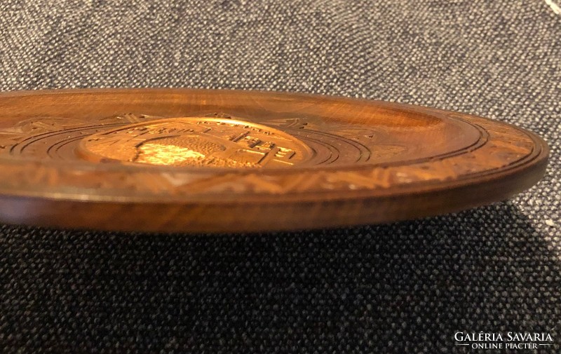 Wooden plate with a metal relief depicting most in the middle