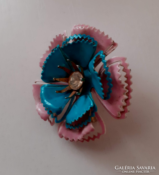 An old handmade enameled metal flower adorned with polished white stone in the middle