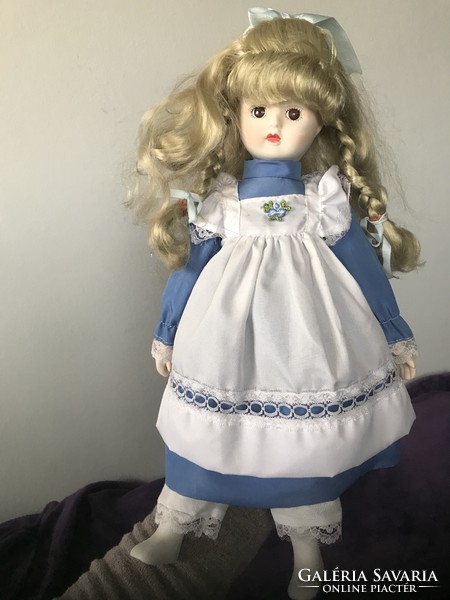 Beautiful blond porcelain doll with old blond hair in blue dress