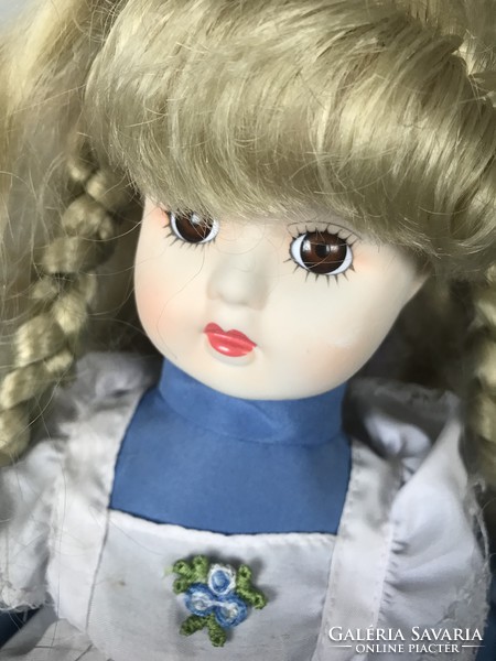 Beautiful blond porcelain doll with old blond hair in blue dress