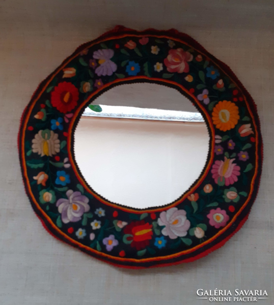 A mirror that can be hung on a wall with old matyó embroidery on an old cloth base