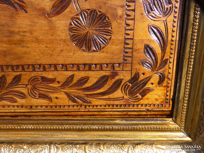 Folk wood carving in gilded picture frame.