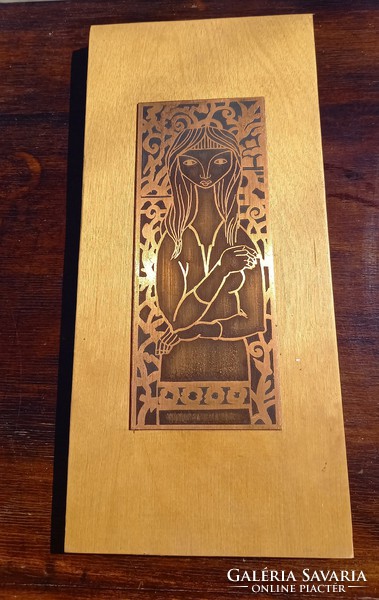 A wooden plaque placed on a wooden base depicting a woman in a wall decoration image