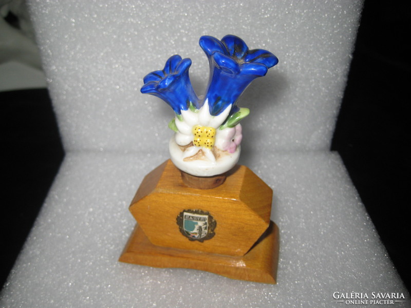 Old porcelain drink spout in a wooden holder with the two most beautiful alpine flowers on it, the ......