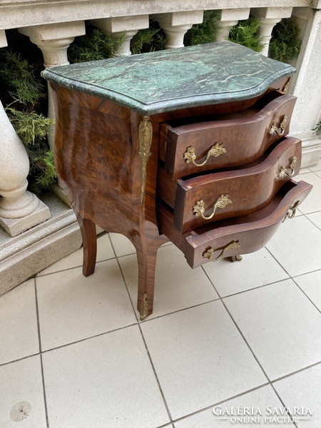 A small chest of drawers with a beautiful bent shape