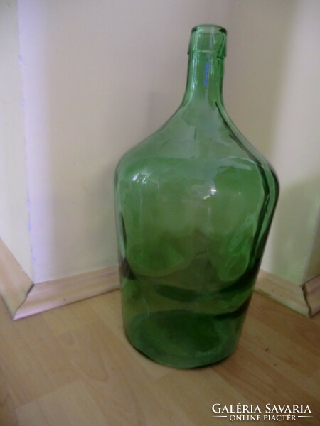 Fresh green glass old demison bottle with lens 5 l. Its silhouette highlights the dotted pattern in the glass
