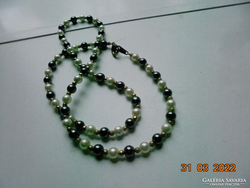 Necklaces made of shiny grayish black mineral, saltwater pearls and gold-colored intermediate pearls