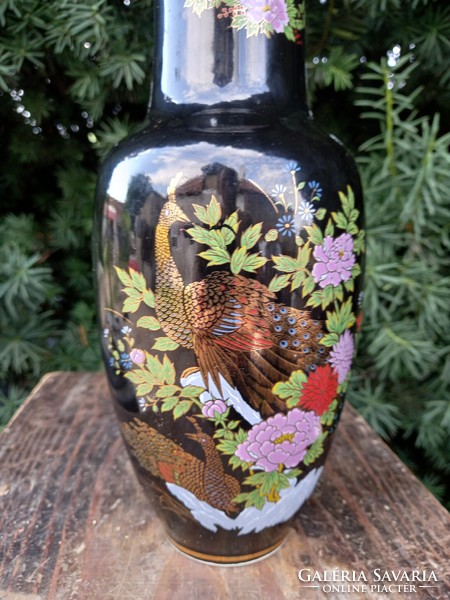 Beautiful Japanese porcelain vase with gold peacocks and flowers on a black background.