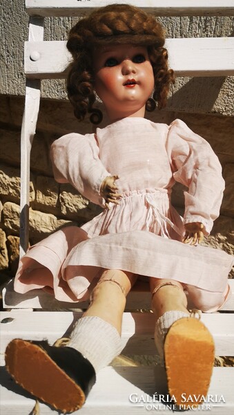 A doll with an antique porcelain head, a wooden body and a beautiful original piece marked with Buskvit
