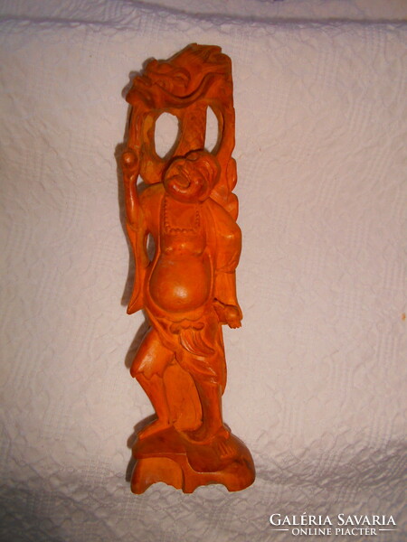 A meticulously crafted carved sandalwood laughing goofy figure with a dragon snake