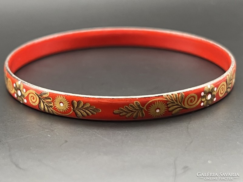 Fire enamel bracelet with a gold flower pattern on a red background