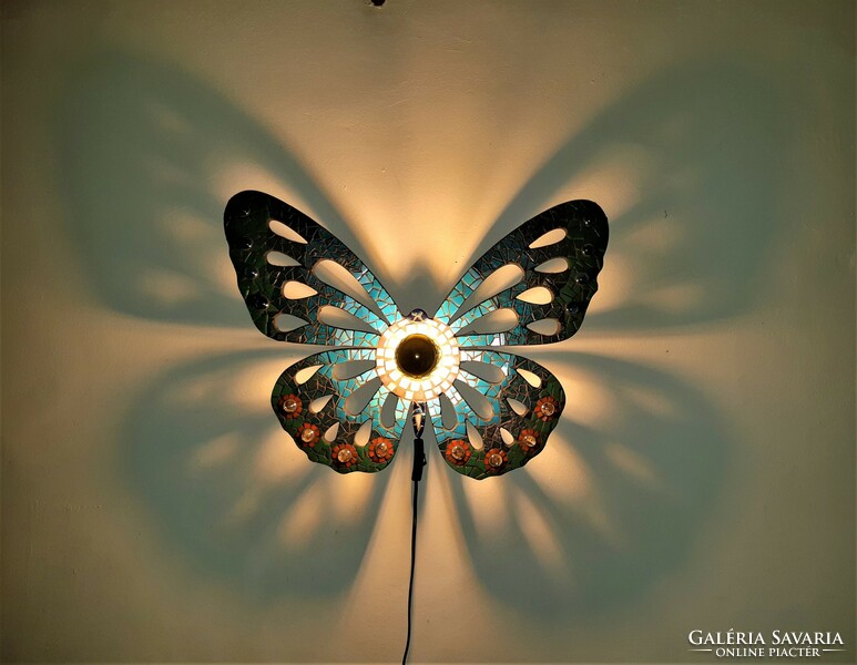 Mosaic-decorated wall lamp casting a shadow. Unique handwork.