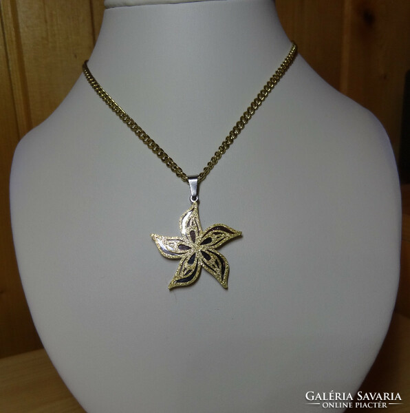 Pendant and chain made of surgical steel in the shape of a flower, with wavy petals sprinkled with golden sand.