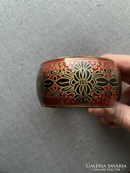 Wider style, decorative copper bracelet painted on a bright red background