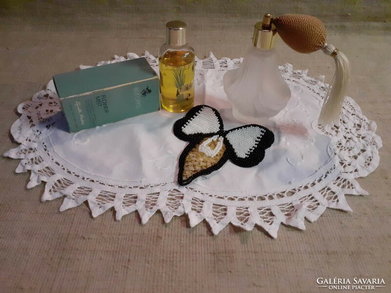 Pump perfume bottle in a Parisian branded perfume box on a small tablecloth with a pearl bow