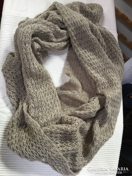 A young, loosely knit drab large round scarf