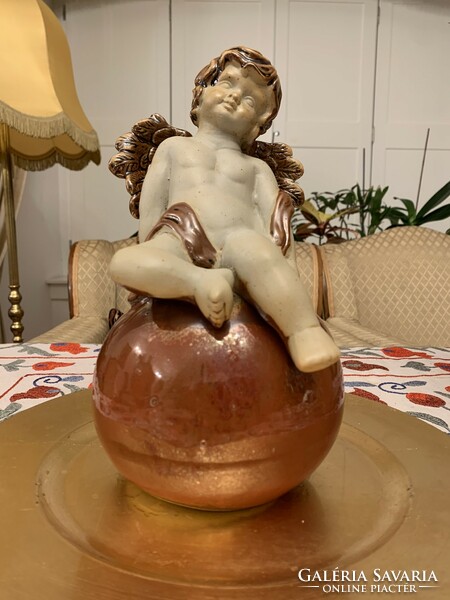 Porcelain angel sitting on an eosin-glazed globe