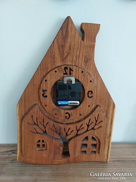 Wall clock in the shape of a house carved from wood