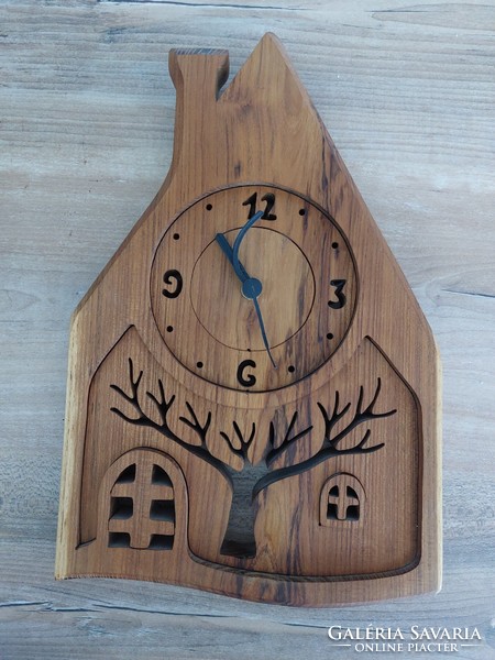 Wall clock in the shape of a house carved from wood