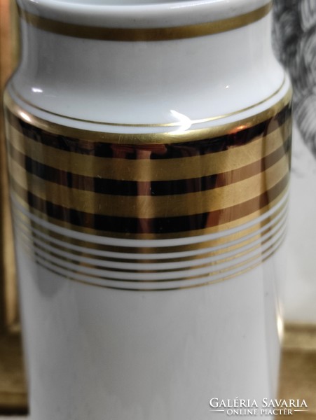 A cylindrical German porcelain vase with gold and black stripes on a white background