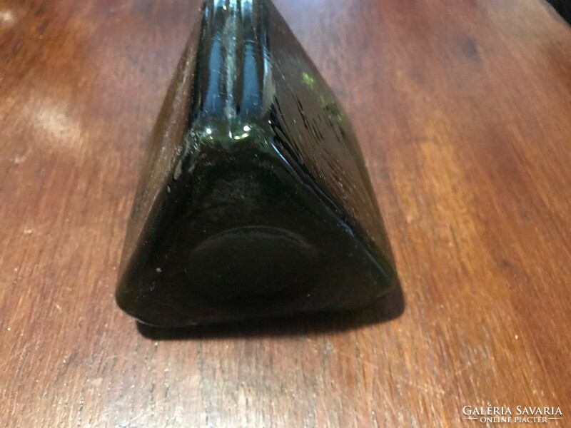 Old ant bitter glass bottle. It is green in color. Triangular shape. 18X10 cm undamaged.