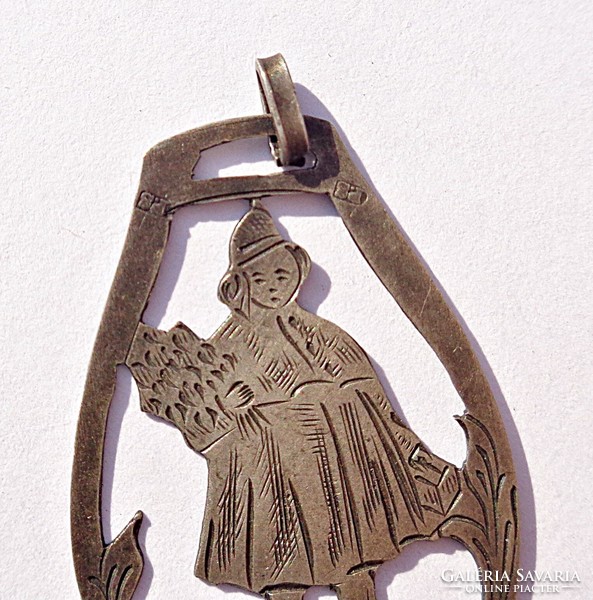 Old silver pendant, girl with a bouquet of flowers and a suitcase