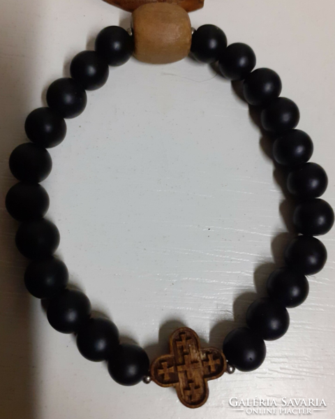 A wooden frame rubber bracelet made of black pebbles in good condition with a carved wooden pendant