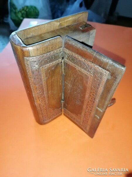 An old, book-shaped, decorative wooden secret box opens interestingly