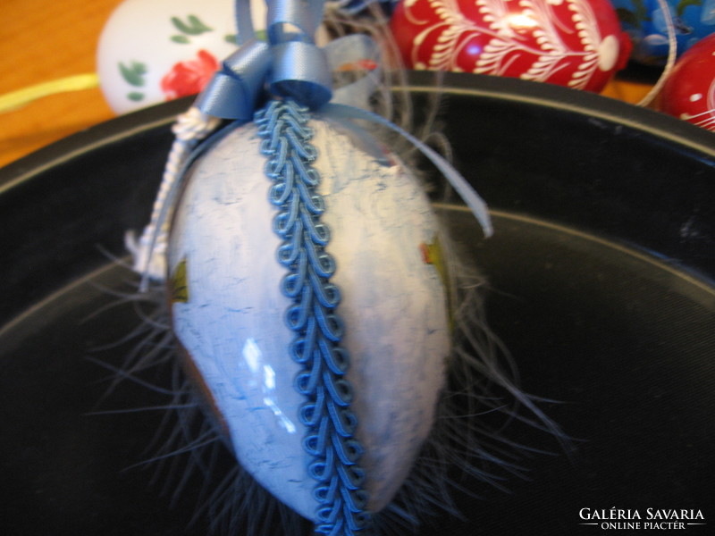 A painted plastic egg with feathers and a bunny inside