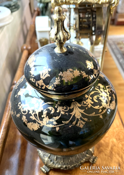 A gilded glass vase with a lid on a bronze base and with tongs