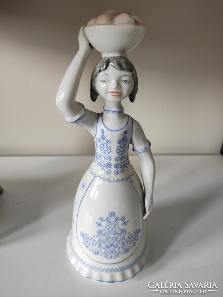 A girl carrying a bowl of Hollóháza scones in blue folk costume, porcelain statue