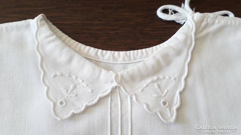 Old shabby baby clothes in traditional costume embroidered on canvas babaing