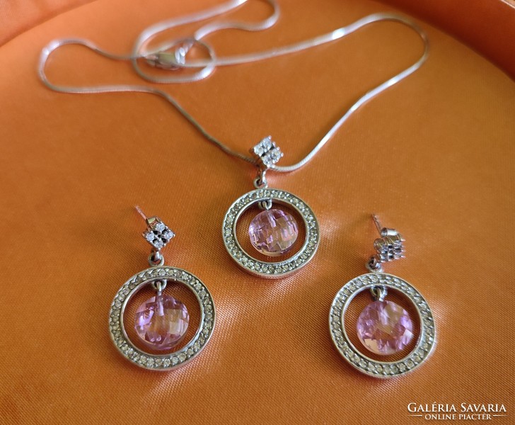 A pair of silver earrings and a chain with a pink stone