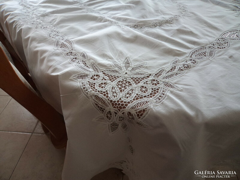 A huge, handmade, richly patterned, snow-white festive tablecloth with a beautiful lace border.