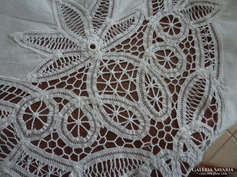 A huge, handmade, richly patterned, snow-white festive tablecloth with a beautiful lace border.