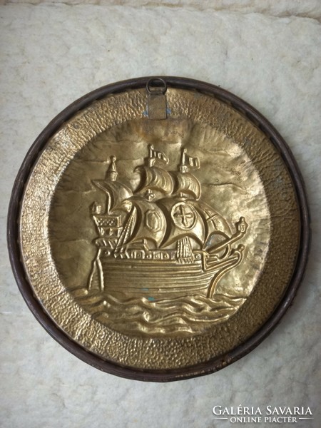 A copper wall plate with a convex ship image