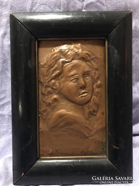 A female portrait hammered out of a red copper plate