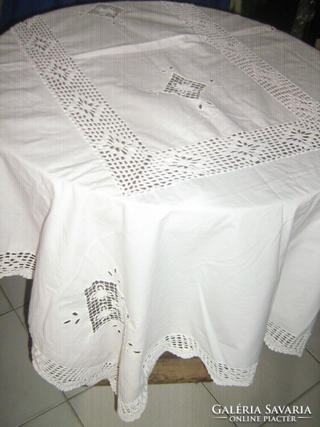 A dreamy white needlework tablecloth with a sewn lace insert with a hand-crocheted edge