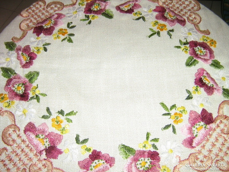 A richly hand-embroidered tablecloth with a beautiful floral lace edge