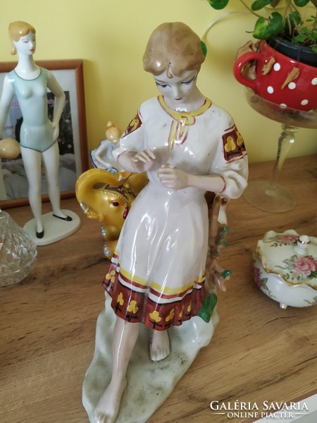 Porcelain figure of a girl picking flowers, in folk costume for sale!