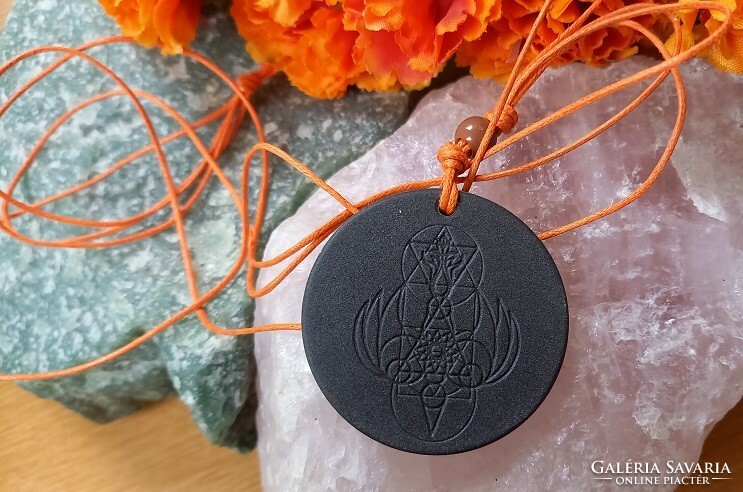 Amulet engraved in volcanic stone, talisman pendant on a string with magical symbols